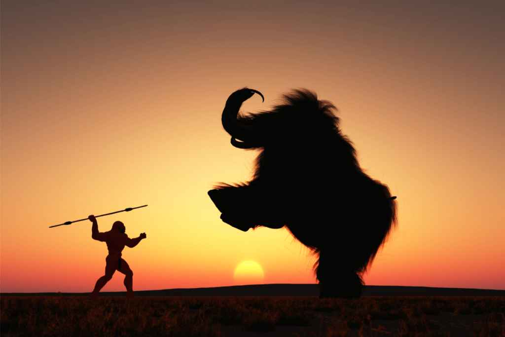 Silhueta de um homem primitivo com uma lança, enfrentando um mamute gigante ao pôr do sol. Evolução da Gastronomia