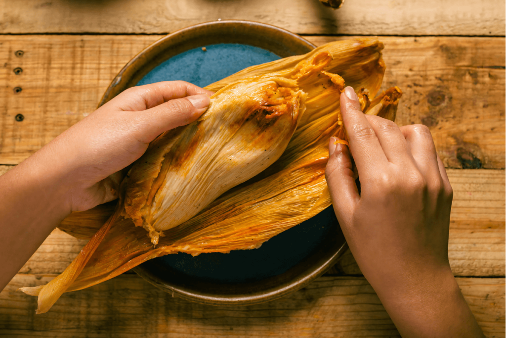 Pessoa abrindo um Tamale com as mãos. Tamale, comida típica mexicana.
Tamales mexicanos com sabor de casa.