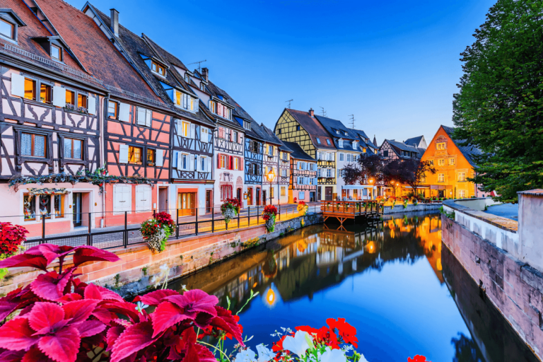 Canal com casas coloridas de enxaimel refletidas na água em Colmar (La Petite Venise), representando o charme da região dos tipos de uva da Alsácia.